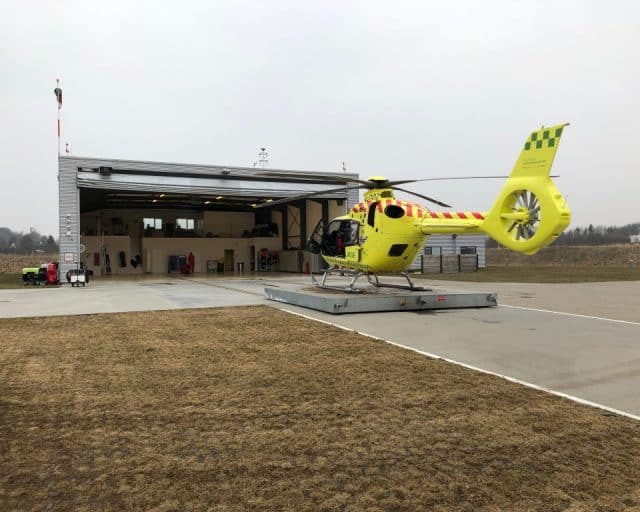 Bilde av basebygg og helikopter parkert utenfor.